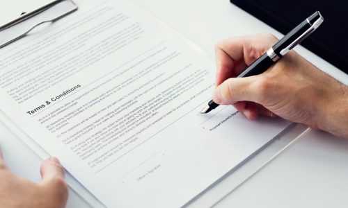 closeup-hand-signing-paper-workspace